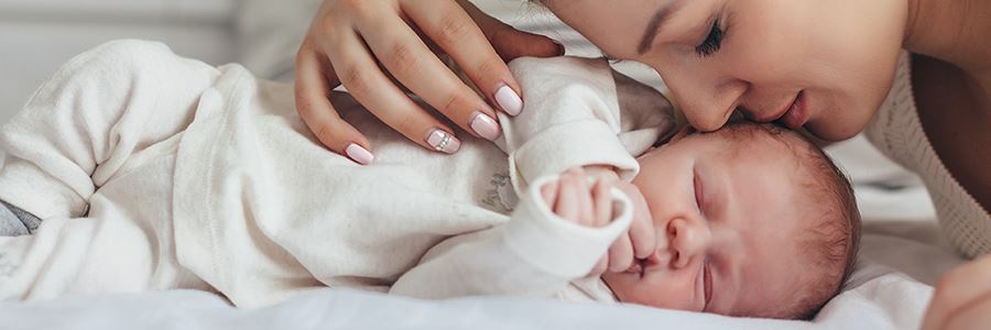 Mutter kuschelt mit Neugeborenem