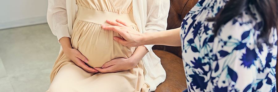 Hebamme bei einer Schwangerschaftsuntersuchung mit einer schwangeren Frau